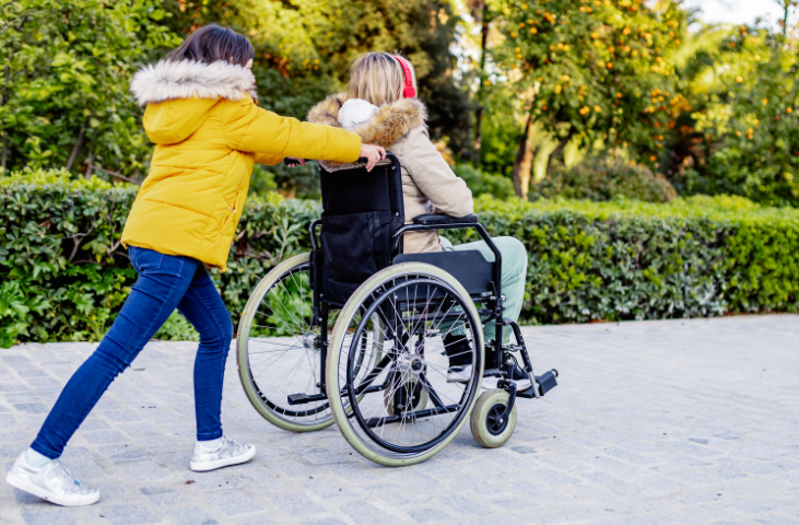 Young carer pushing her Mum in a wheelchair