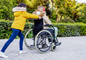 Young carer pushing her Mum in a wheelchair